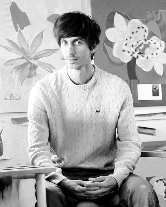 Kubi Vasak seated in front of three of his collage works